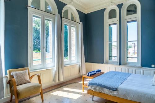 佩兹纳斯Ultimate Relaxation for Family or Group at Renowned Couvent des Ursulines, a Tranquil Escape in Historic Pézenas的卧室拥有蓝色的墙壁,配有一张床和椅子