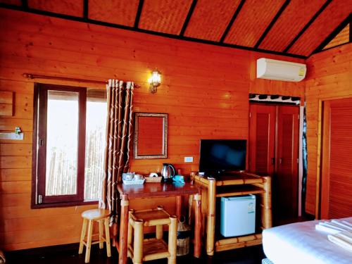 涛岛宝通海滩度假酒店的一间卧室配有一张桌子、一台电视和一张床