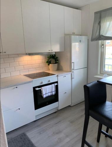 特罗尔海坦Glöm dina bekymmer i denna rymliga lägenhet的厨房配有白色橱柜、炉灶和冰箱。
