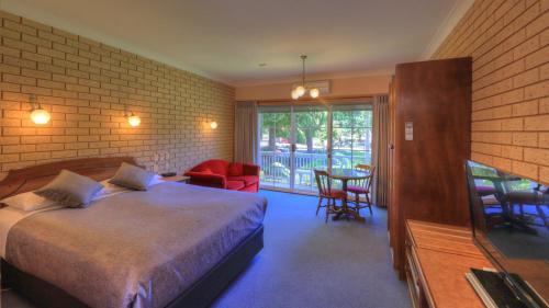 布赖特Barrass's John Bright Motor Inn的卧室配有一张床和一张桌子及椅子