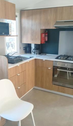 塞尼奥斯Mobil home spacieux的厨房配有木制橱柜和白色椅子