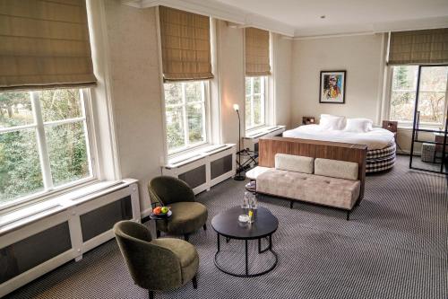 沃尔堡Central Park Voorburg - Relais & Chateaux的酒店客房配有一张床、一张沙发和椅子。