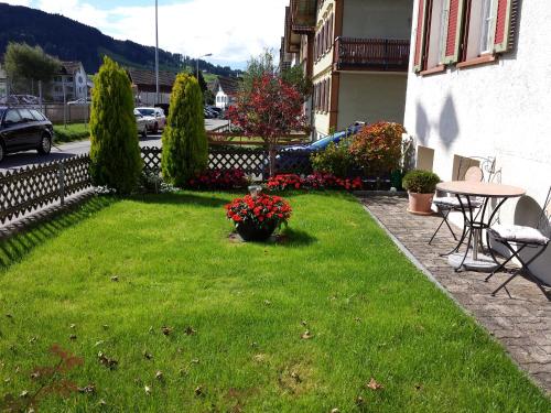 阿彭策尔Ferienzimmer Appenzell的一个带桌子的院子和一个带鲜花的草坪