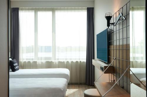 霍夫多普Moxy Amsterdam Schiphol Airport的酒店客房设有两张床和电视。