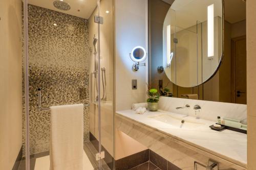 多哈Embassy Suites By Hilton Doha Old Town的一间带水槽、淋浴和镜子的浴室