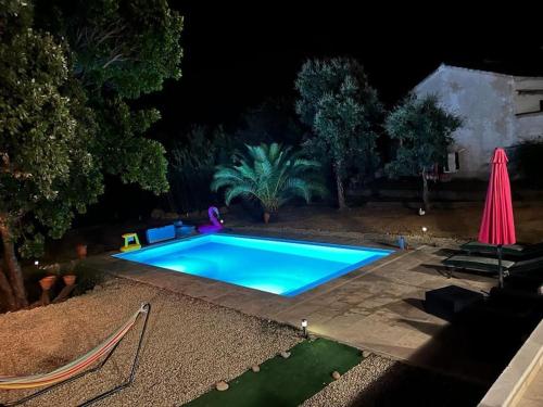 文蒂塞里Maison de vacances的游泳池(晚上配有粉红色遮阳伞)
