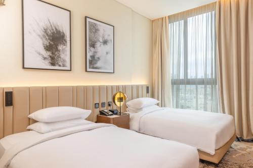 多哈Embassy Suites By Hilton Doha Old Town的配有窗户的酒店客房内的两张床