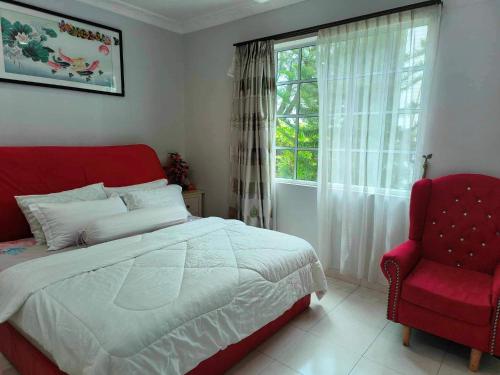 金宝Trails of Kampar Villa Homestay的一间卧室配有一张床、一张红色椅子和一个窗户