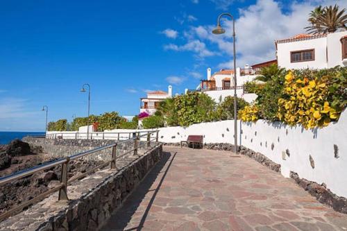 圣地亚哥港Govimar Tenerife的一条有黄色花朵的白色墙壁旁的走道