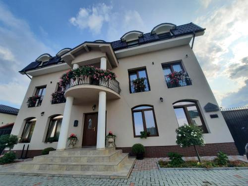 莱斯诺夫AristoCat Hotels Rasnov的带阳台和楼梯的白色房屋