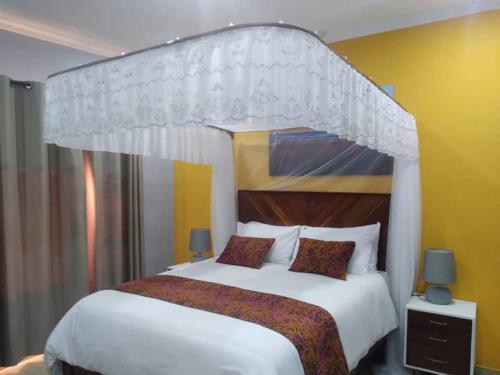 YadingaKAWETA COTTAGE的一间卧室配有一张带天蓬的大型白色床