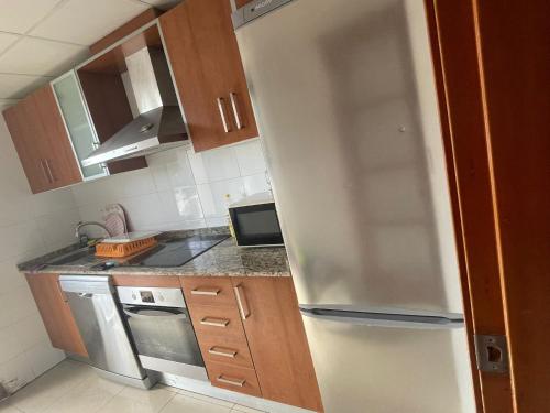 克萨达城Albamar的厨房配有白色冰箱和木制橱柜。