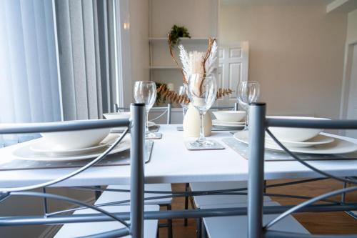 伯肯黑德Entire House-Merseyside-Liverpool的白色的餐桌,配有椅子和眼镜