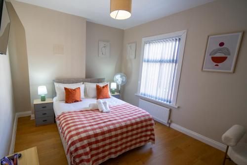 伯肯黑德Entire House-Merseyside-Liverpool的一间卧室配有一张带条纹毯子的床和窗户