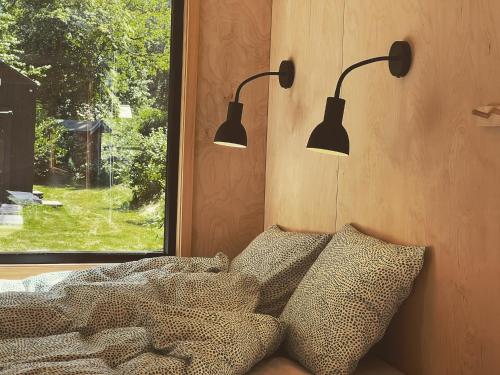 彻默岛Elevated Tiny House Glamping的卧室配有两盏灯,位于床上方,设有窗户