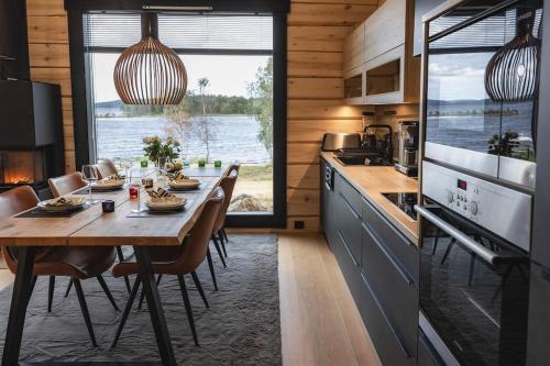 伊纳利Upea Villa Lapin Kulta hirsihuvila Inarijärven rannalla的带桌椅的厨房和带大窗户的厨房