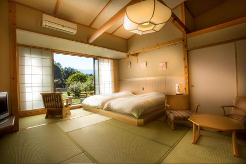 木曾町风里茑屋季日式旅馆的一间卧室设有一张床和一个大窗户