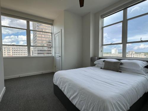 巴吞鲁日Stylish Downtown High-Rise - 2BD的白色卧室设有大窗户和床