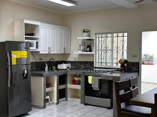 ChalchuapaChalchuapa, Santa Ana La Casa de Sussy, El Salvador的厨房配有白色橱柜和黑色冰箱。
