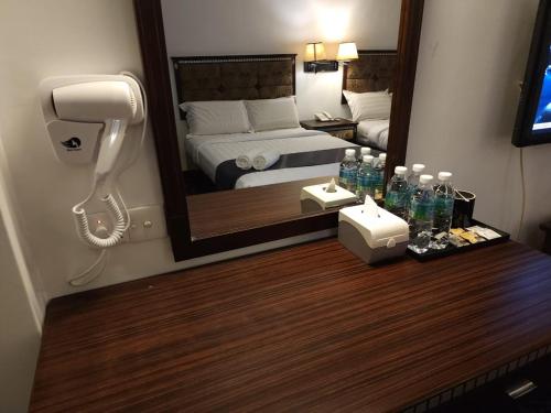 关丹Go Lodge Hotel Kuantan的酒店客房带镜子,桌子上还有电话