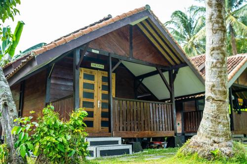 比哈尔Sumatra Surf Resort的一座木房子,前面有一棵棕榈树