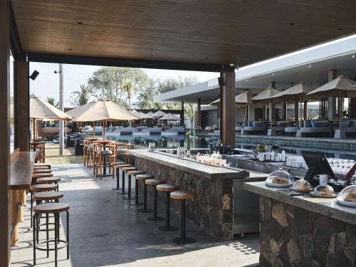 吉利美诺BASK Gili Meno的餐厅设有酒吧凳子、桌子和遮阳伞