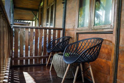 比哈尔Sumatra Surf Resort的小屋门廊上摆放着三把椅子