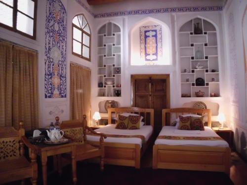 布哈拉埃米尔住宿加早餐旅馆的客房设有两张床、两张桌子和一扇窗户。