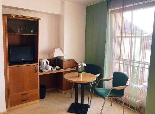 卡尔斯特卡尔斯特经典酒店的酒店客房配有桌椅和电视。