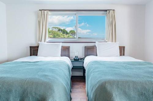 Harada白浜大洋マンション的带窗户的客房内的两张床