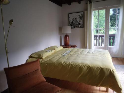 巴涅尔-德吕雄La dépendance的一间卧室设有一张床、一个窗口和一把椅子