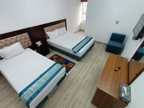 达卡Hotel D-Palace的酒店客房,配有两张床和椅子
