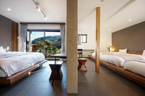 热海VILLA ATAMI -Nagomi-的一间卧室设有两张床和大窗户