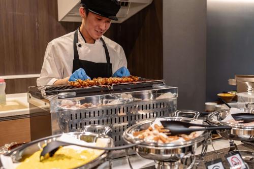 高山Relax Hotel Takayama Station的厨师在餐厅厨房准备食物