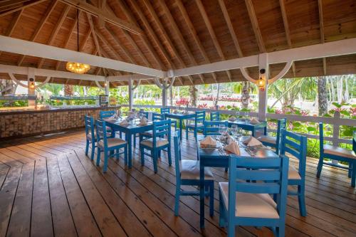 拉斯特拉纳斯Viva V Samana by Wyndham, A Trademark Adults All Inclusive的木甲板上设有蓝色桌椅的餐厅
