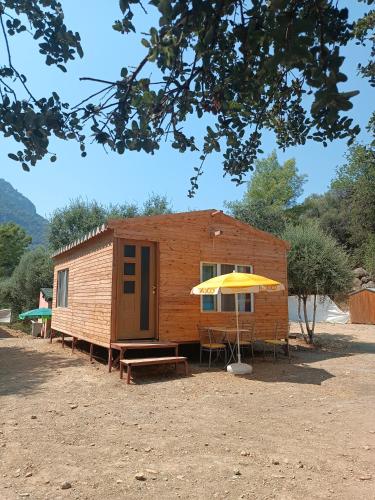 穆拉Eses Camping的小屋配有桌子和黄色雨伞
