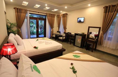 美奈Saigon Emerald Beach Resort的酒店客房设有两张床、一张桌子和一台电视。