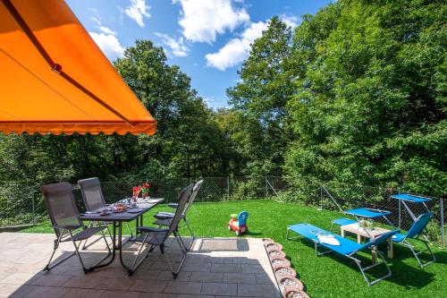 卢加诺Ca' Mia Panoramica - Happy Rentals的庭院配有桌椅和橙色遮阳伞。