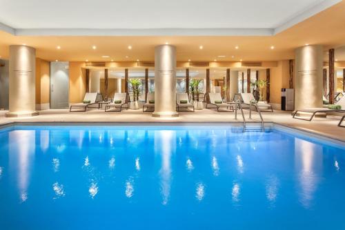 马德里马德里公主美利亚酒店的酒店的大型游泳池配有桌椅