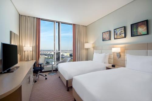 阿可贺巴Hilton Garden Inn Al Khobar的酒店客房设有两张床和一张书桌及电视