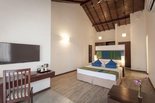 帕西库达平静度假村的一间卧室配有一张床、一张书桌和一台电视。