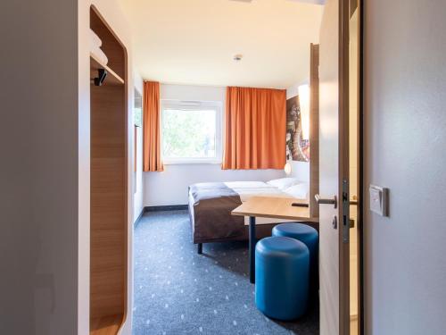 奥格斯堡B&B Hotel Augsburg-Süd的酒店客房设有床、桌子和窗户。