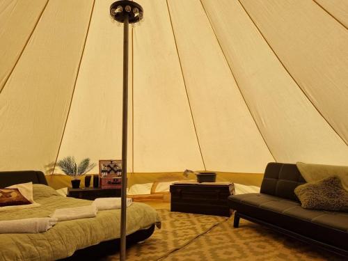 IfieldGlamping in style Bell tent的一个带一张沙发和一张桌子的帐篷的房间