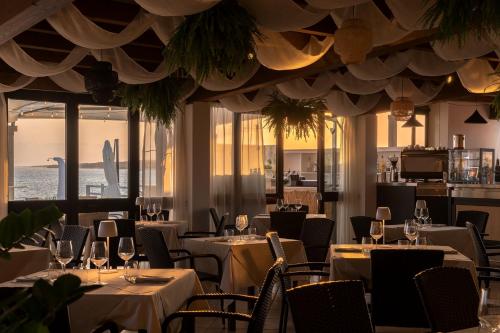 普佐伊杜Hotel da Cesare Maluentu的餐厅设有白色的桌椅和窗户。