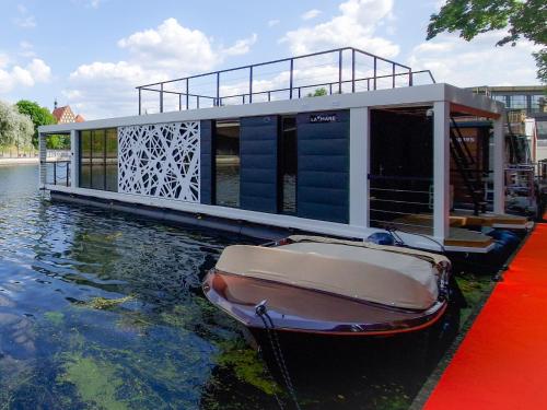 比得哥什Dom na wodzie LaMare Modern 14的坐在房子旁边的水中的小船