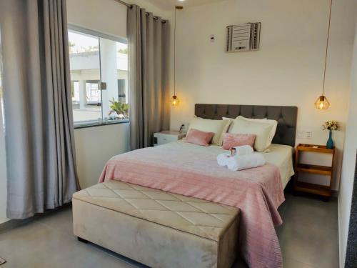 瓜拉派瑞CHALÉS GUARAÍPE的卧室配有一张带粉红色枕头的大床