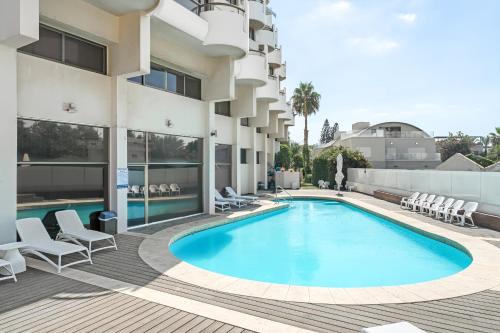 荷兹利亚Elegant Beachfront Duplex with Private Parking的一座带椅子的酒店游泳池以及一座建筑