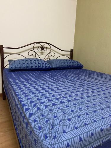 关丹ADEELA HOMESTAY @ BANDAR KUANTAN的一张带蓝色棉被和枕头的床