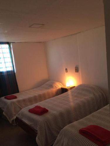 马拉圭Eluney的一间设有两张床铺的房间,配有红色毛巾