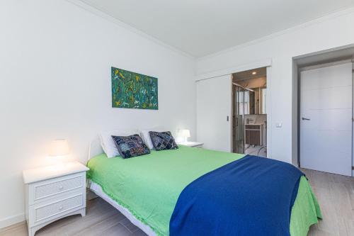 阿玛考德佩拉Vieira Azul的白色的卧室设有一张绿色的床和墙上的绘画作品